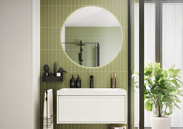 Ein modernes Bad mit einem stilvollen Waschbecken, runder Spiegel und grünen Fliesen schafft ein einladendes Ambiente.  | © Name