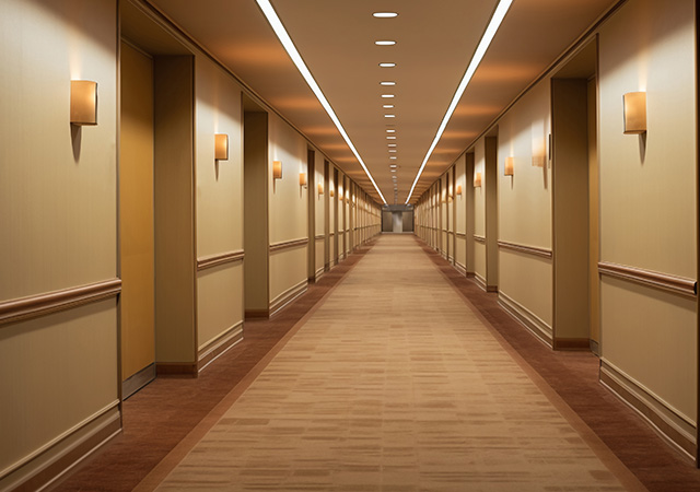 Ein eleganter Hotel-Flur mit warmem Licht, der die Gäste zu den Zimmern führt und eine einladende Atmosphäre schafft.
