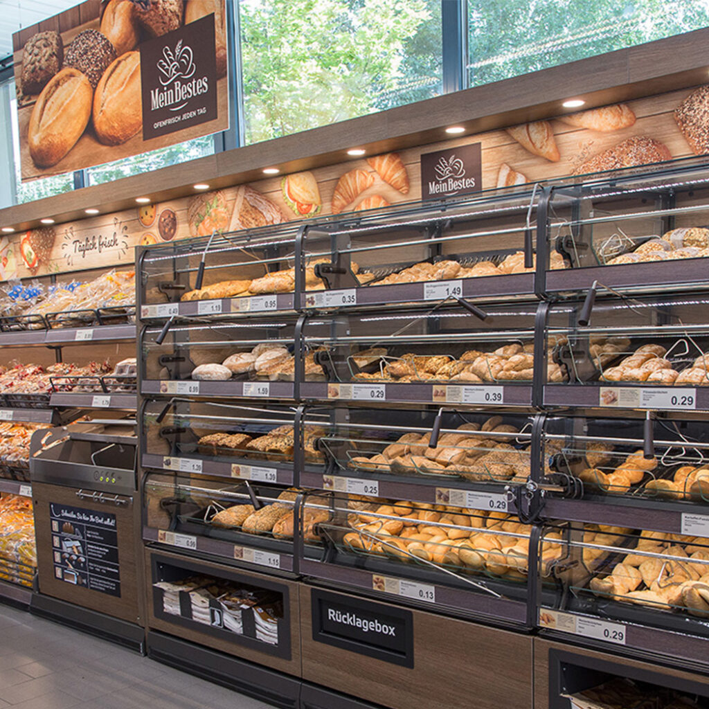 Eine ansprechend gestaltete Ladenbau-Backstation zeigt eine Vielzahl frischer Brötchen und Backwaren in der Auslage.