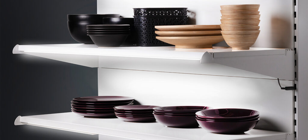 Ein modernes Regalsystem zeigt stilvolle Schalen und Teller, beleuchtet von einem eleganten Lichtsystem.