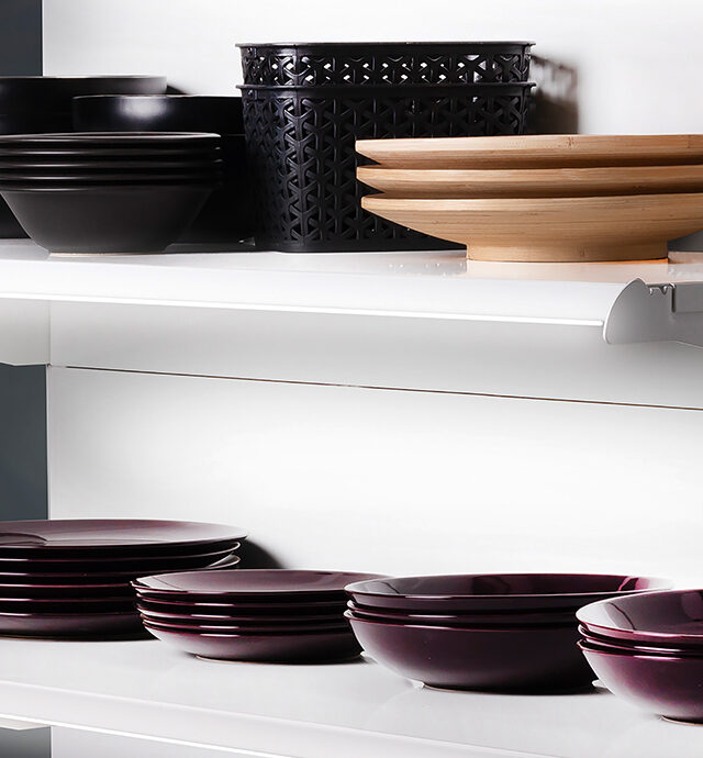 Ein modernes Regalsystem zeigt stilvolle Schalen und Teller, beleuchtet von einem eleganten Lichtsystem.
