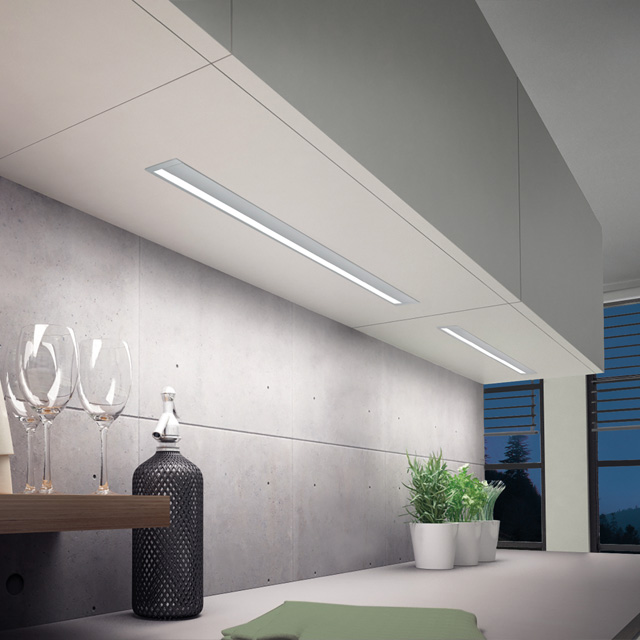 Elegante graue Küche mit indirekter Beleuchtung, stilvollen Gläsern und modernen Akzenten auf der Arbeitsplatte.