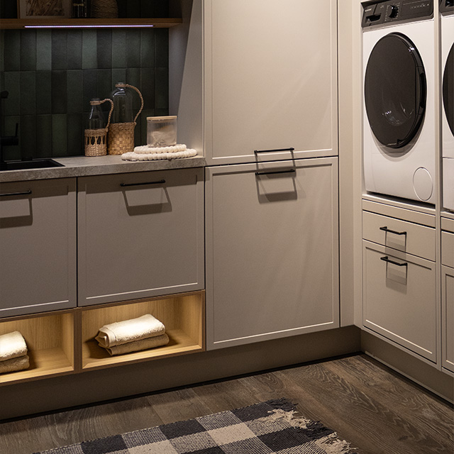 Moderne Waschküche mit eleganten Schränken, Waschmaschine und warmem Licht, das eine einladende Atmosphäre schafft. 