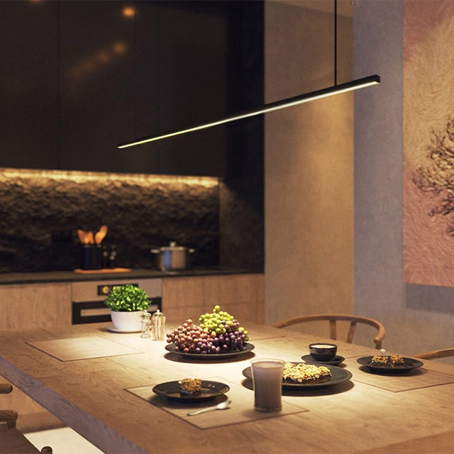 Ein moderner Essbereich mit eleganter Beleuchtung, frischen Früchten und gedecktem Tisch für geselliges Beisammensein