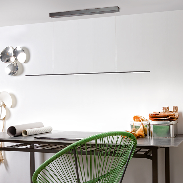 Ein stilvoller Arbeitsbereich mit einer minimalistischen LED-Leuchte und einem modernen grünen Stuhl schafft ein angenehmes Ambiente.