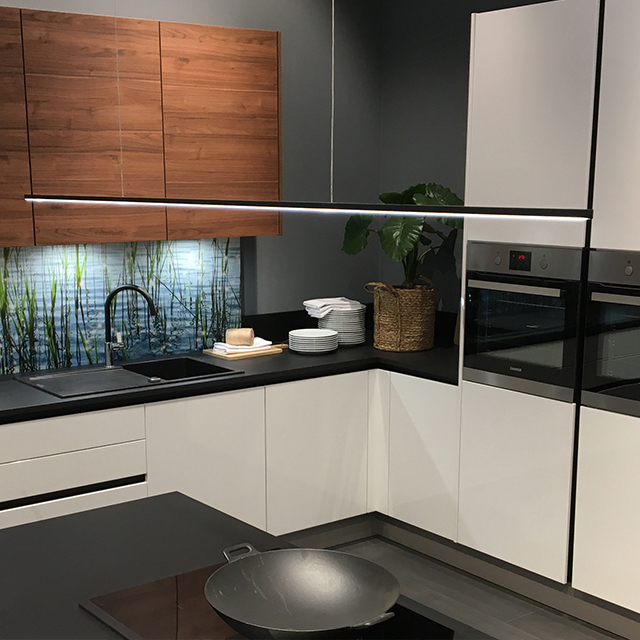 Moderne Küche mit eleganter Beleuchtung, Holzverkleidung und stilvollen Geräten, die eine einladende Atmosphäre schaffen.