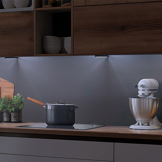 Dunkle Küche mit beleuchteter Arbeitsplatte mit Kochfeld und Küchenmaschine