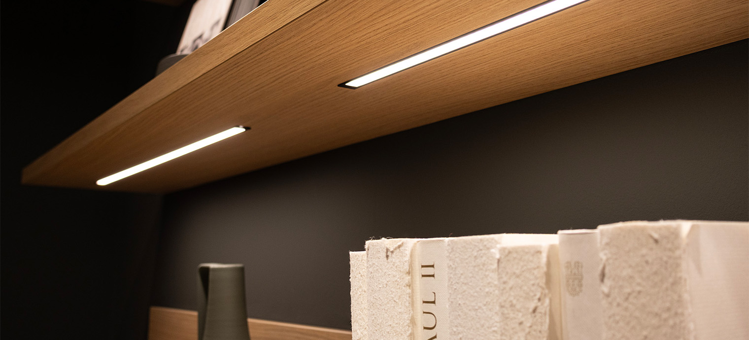 Eine moderne Regalwand mit sanfter Beleuchtung setzt stilvolle Akzente und schafft eine einladende Atmosphäre im Raum.