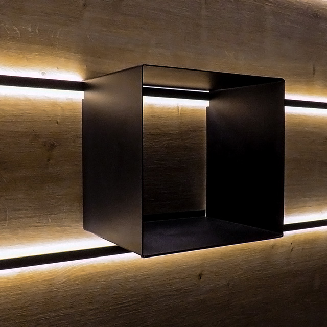 An elegant black display cabinet is mounted on an illuminated wooden wall, adding a stylish touch.