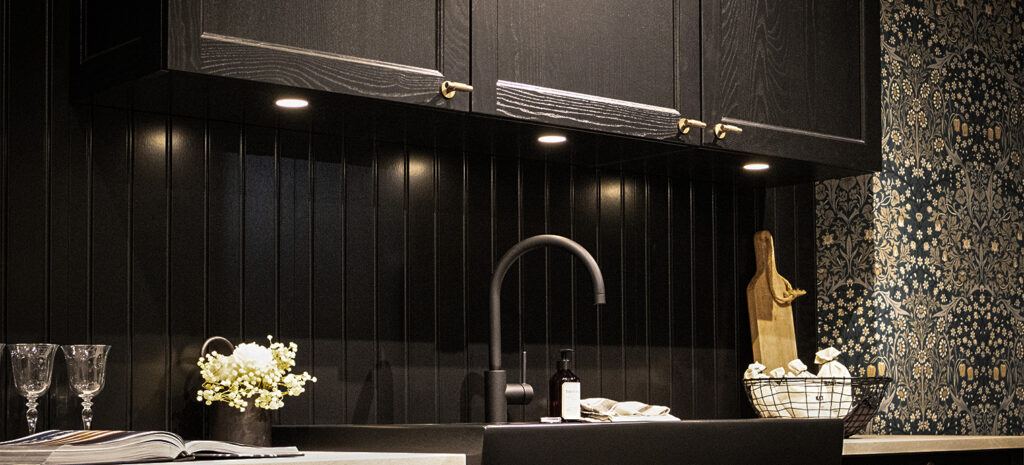 Eine moderne Küche mit einem schwarzen Oberschrank und stilvoller Beleuchtung, die den Raum elegant akzentuiert.