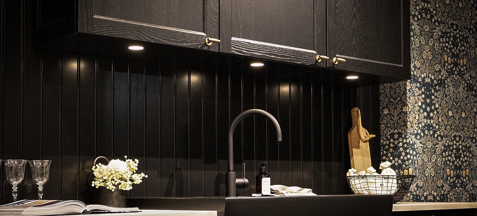 Eine moderne Küche mit einem schwarzen Oberschrank und stilvoller Beleuchtung, die den Raum elegant akzentuiert.