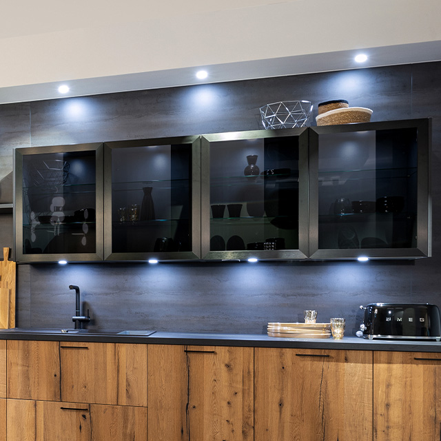 Moderne Küchenzeile mit eleganten Hängeschränken und stimmungsvollem Licht, das die Möbel hervorhebt.