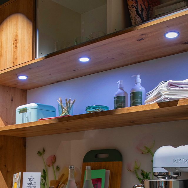 Eine stilvolle ld8201al-f55-regalwand mit LED-Beleuchtung präsentiert Küchenutensilien und Dekoration auf Holzregalen.