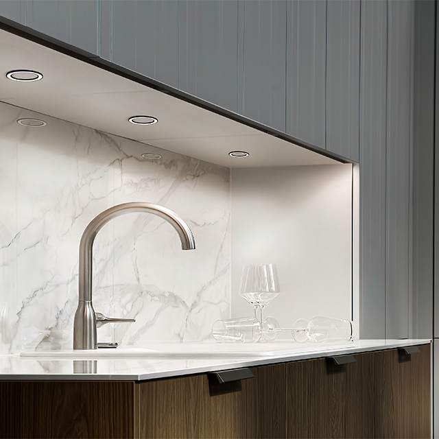 Moderne Küchenszene mit eleganter Spüle, Marmorplatte und geschmackvoller Beleuchtung unter den Oberschränken