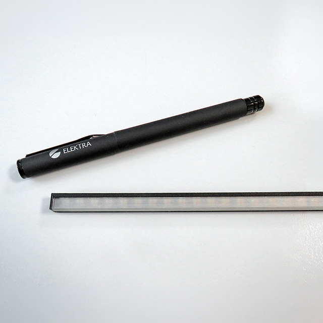 Schwarze Linearleuchte auf neutralem Hintergrund mit Schreibstift im Größenvergleich