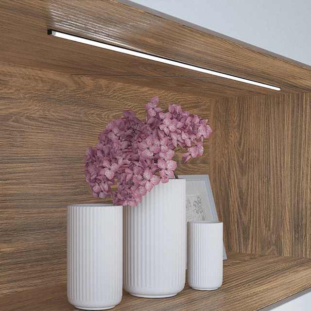 Holzregal mit weißen Dekorvasen und fliederfarbenen Pflanzen. Beleuchtung von oben durch eine LD 8288 Linearleuchte.