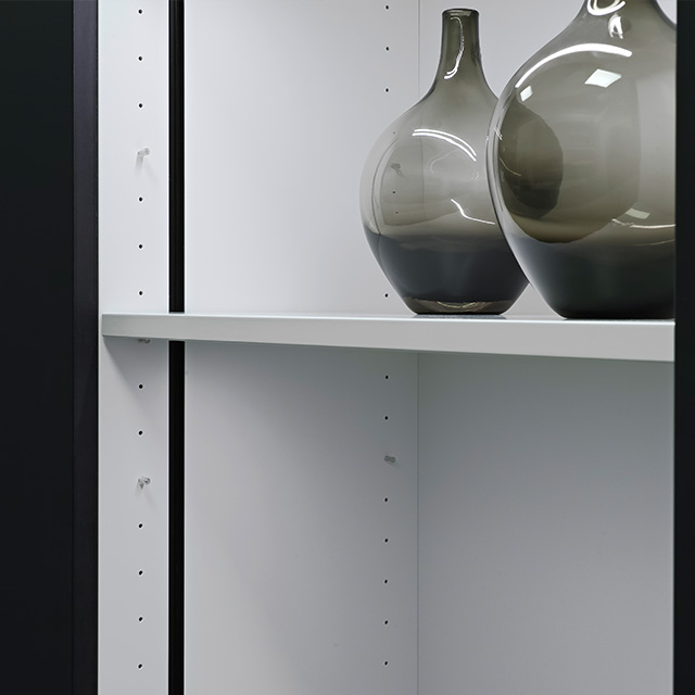 Ein eleganter vario-anwendung-schrank zeigt stilvolle Glasvasen auf einem hellen Regal in einem modernen Raum.